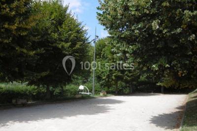 Aire de jeux extérieure avec toboggan, balançoires et structures en bois, entourée de pelouse et d'arbres.