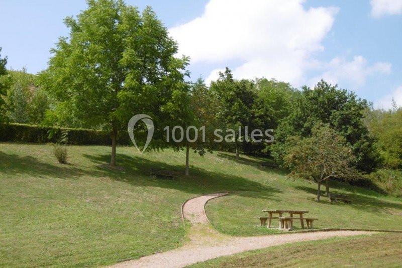Chemin sinueux traversant un parc verdoyant avec arbres, pelouse et une table de pique-nique en bois.