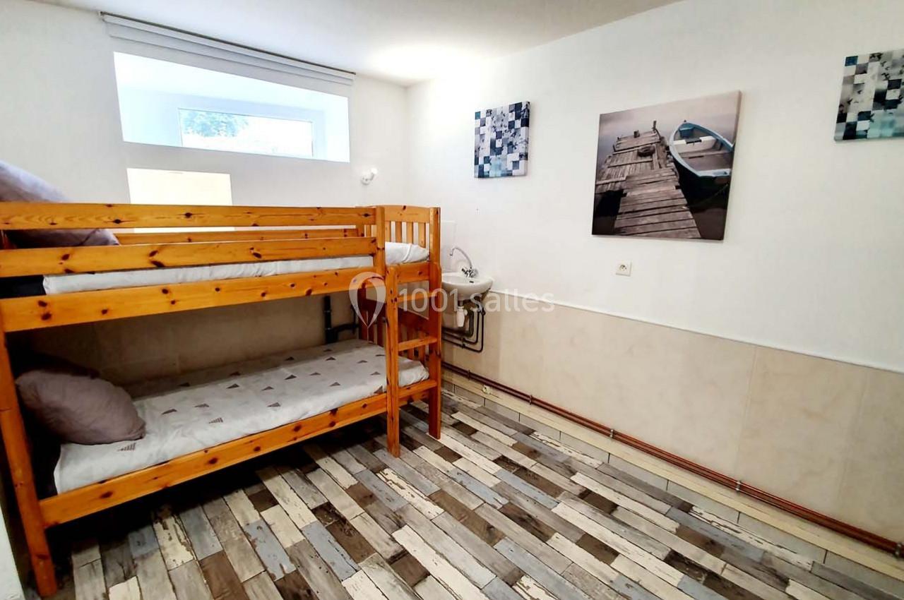 Chambre avec lits superposés en bois, sol en parquet clair, lavabo et décorations murales représentant un ponton.