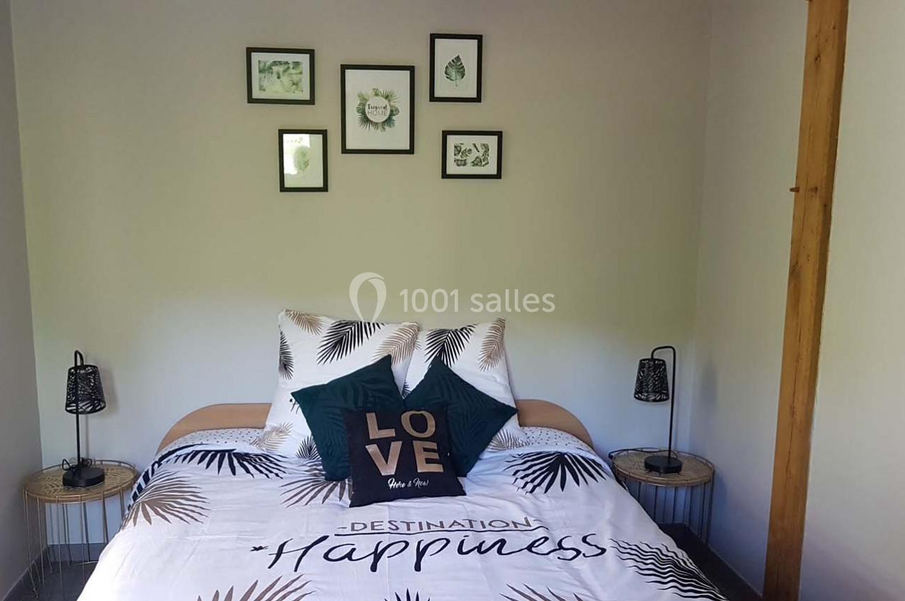 Lit double avec housse de couette à motifs tropicaux, coussins décoratifs et cadres muraux dans une chambre lumineuse.