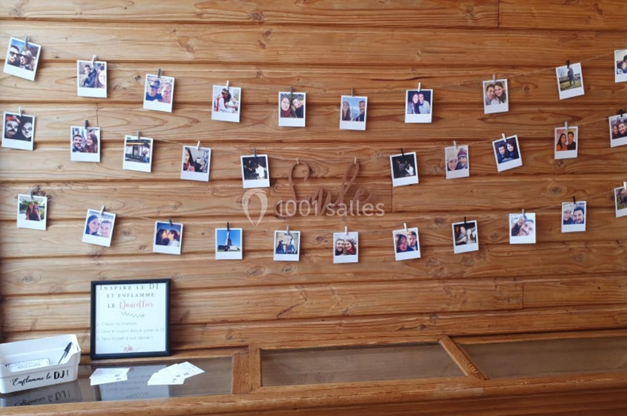 Mur en bois décoré de photos instantanées suspendues sur des fils, avec une inscription ’Smile’ au centre.