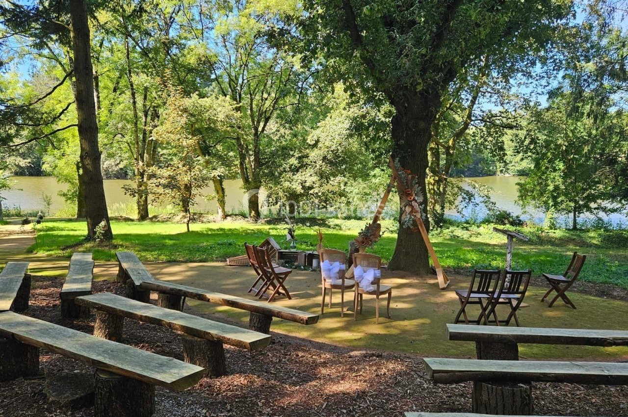 Bancs en bois disposés en plein air face à un lac entouré d'arbres, sous un ciel dégagé.