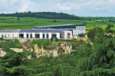 Bâtiment moderne éclairé la nuit, entouré d'un espace extérieur sombre avec un ciel nuageux en arrière-plan.