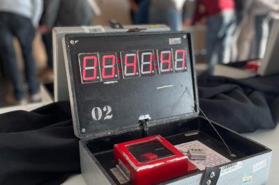 Bâtiment moderne éclairé la nuit, entouré d'un espace extérieur sombre avec un ciel nuageux en arrière-plan.