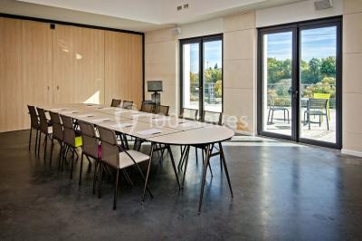 Bâtiment moderne éclairé la nuit, entouré d'un espace extérieur sombre avec un ciel nuageux en arrière-plan.