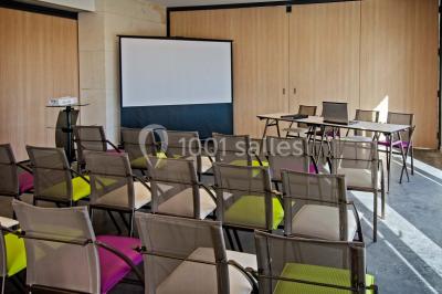 Bâtiment moderne éclairé la nuit, entouré d'un espace extérieur sombre avec un ciel nuageux en arrière-plan.