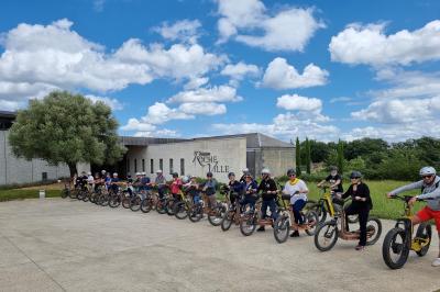 Bâtiment moderne éclairé la nuit, entouré d'un espace extérieur sombre avec un ciel nuageux en arrière-plan.