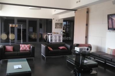 Bâtiment moderne éclairé la nuit, entouré d'un espace extérieur sombre avec un ciel nuageux en arrière-plan.