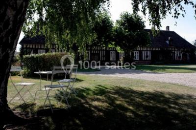 Chambre lumineuse avec poutres apparentes, lit double, table blanche, et vue sur un balcon avec verdure.