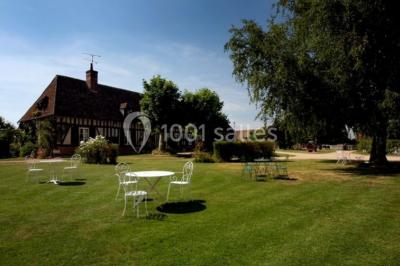 Chambre lumineuse avec poutres apparentes, lit double, table blanche, et vue sur un balcon avec verdure.