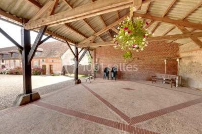 Chambre lumineuse avec poutres apparentes, lit double, table blanche, et vue sur un balcon avec verdure.