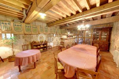 Chambre lumineuse avec poutres apparentes, lit double, table blanche, et vue sur un balcon avec verdure.