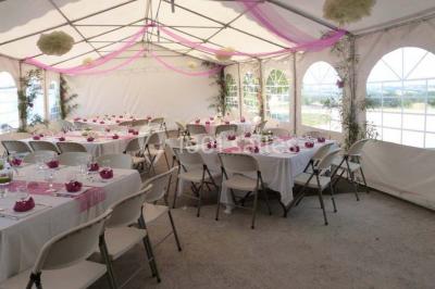 Salle de réception décorée avec des tables dressées, nappes blanches et éclairage chaleureux.
