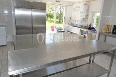 Salle de réception décorée avec des tables dressées, nappes blanches et éclairage chaleureux.
