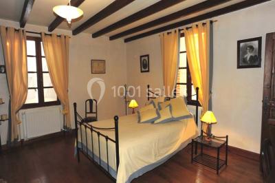 Salle de réception décorée avec des tables dressées, nappes blanches et éclairage chaleureux.