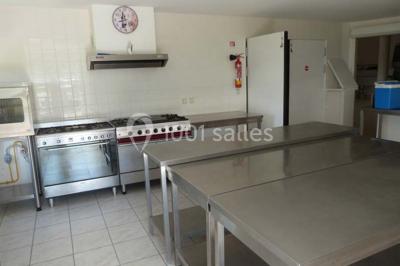 Salle de réception décorée avec des tables dressées, nappes blanches et éclairage chaleureux.