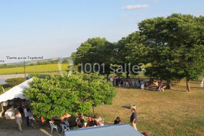 Salle de réception décorée avec des tables dressées, nappes blanches et éclairage chaleureux.