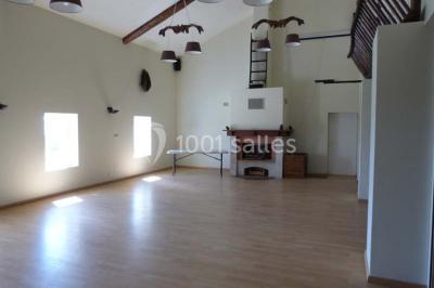 Salle de réception décorée avec des tables dressées, nappes blanches et éclairage chaleureux.