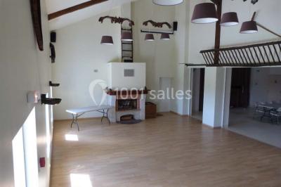 Salle de réception décorée avec des tables dressées, nappes blanches et éclairage chaleureux.