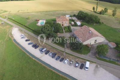 Salle de réception décorée avec des tables dressées, nappes blanches et éclairage chaleureux.