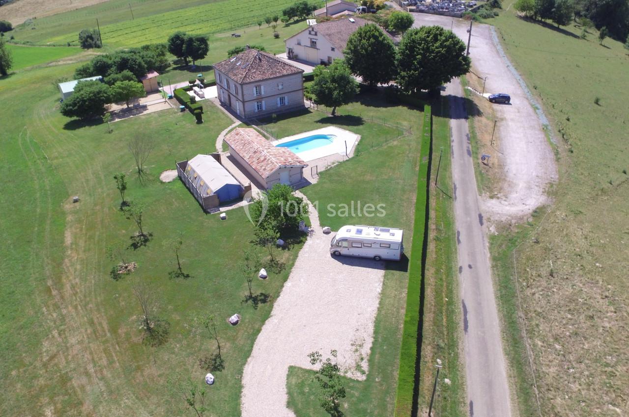 Vue aérienne d'une maison avec piscine, jardin, allée gravillonnée et camping-car stationné dans un cadre rural.