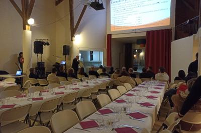 Salle de réception décorée avec des tables dressées, nappes blanches et éclairage chaleureux.
