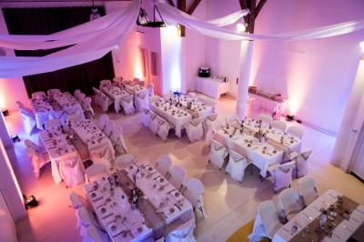Salle de réception décorée avec des tables dressées, nappes blanches et éclairage chaleureux.