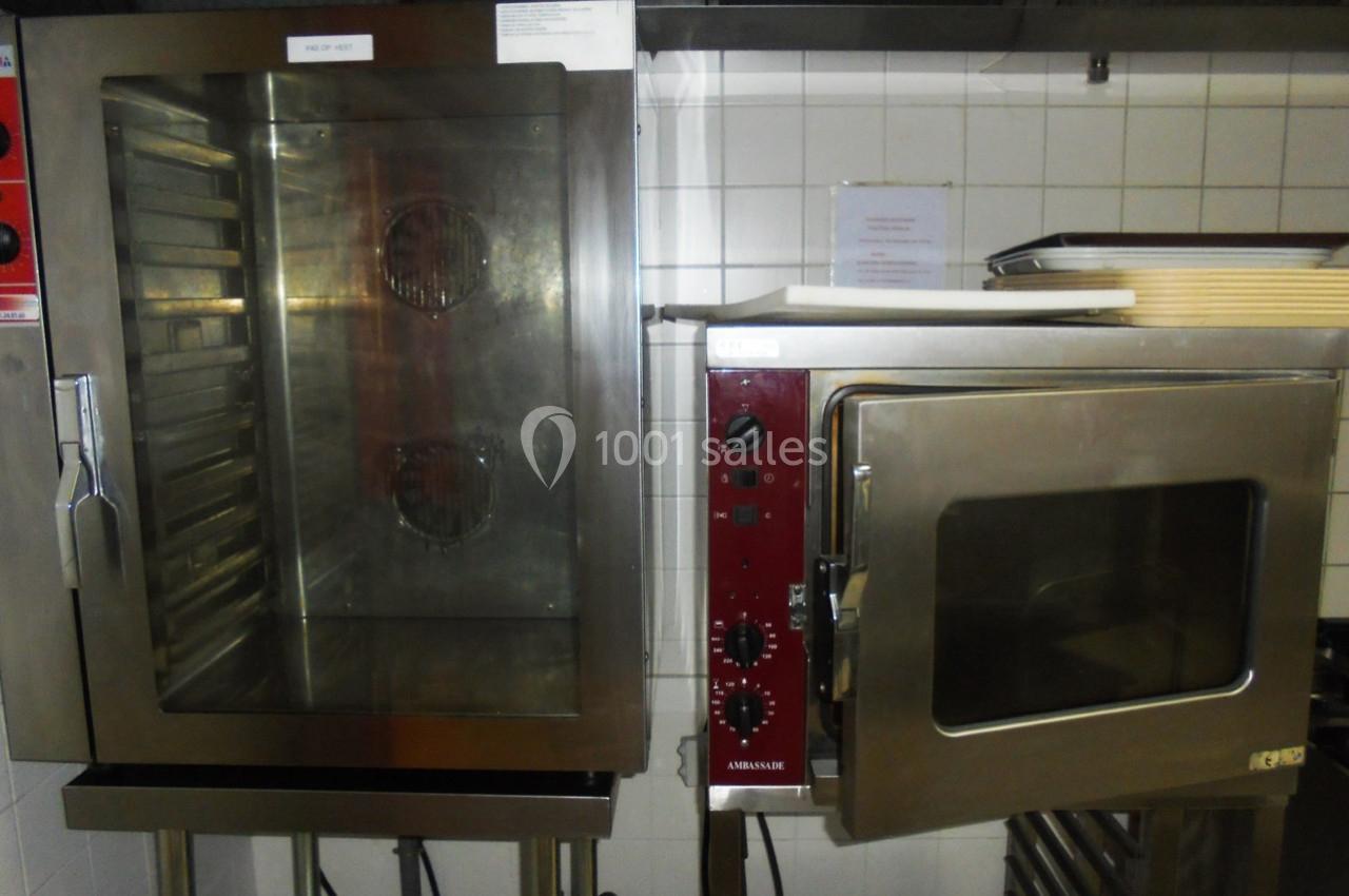 Deux fours professionnels en acier inoxydable dans une cuisine carrelée, l'un ouvert et l'autre fermé.