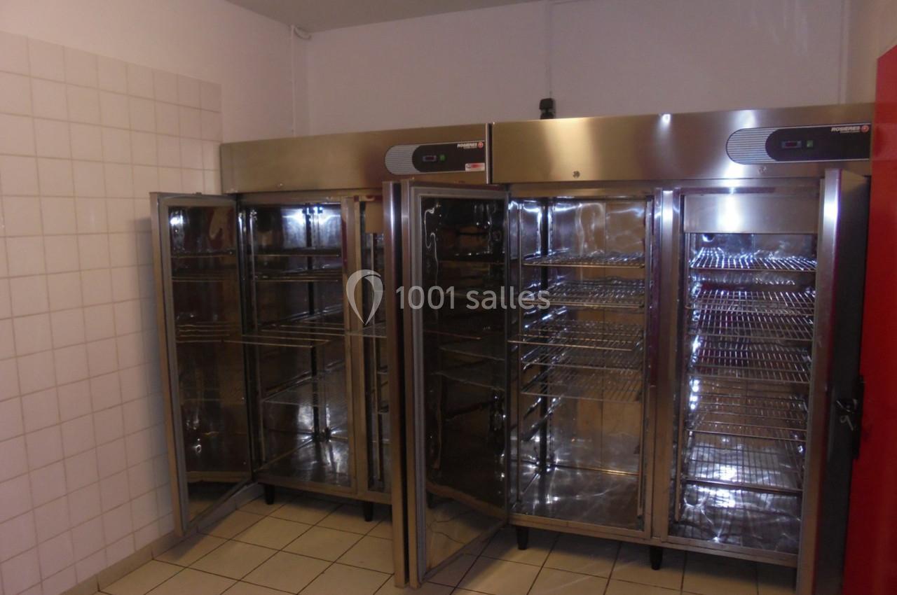 Deux grandes armoires réfrigérées en acier inoxydable avec portes vitrées ouvertes dans une pièce carrelée.