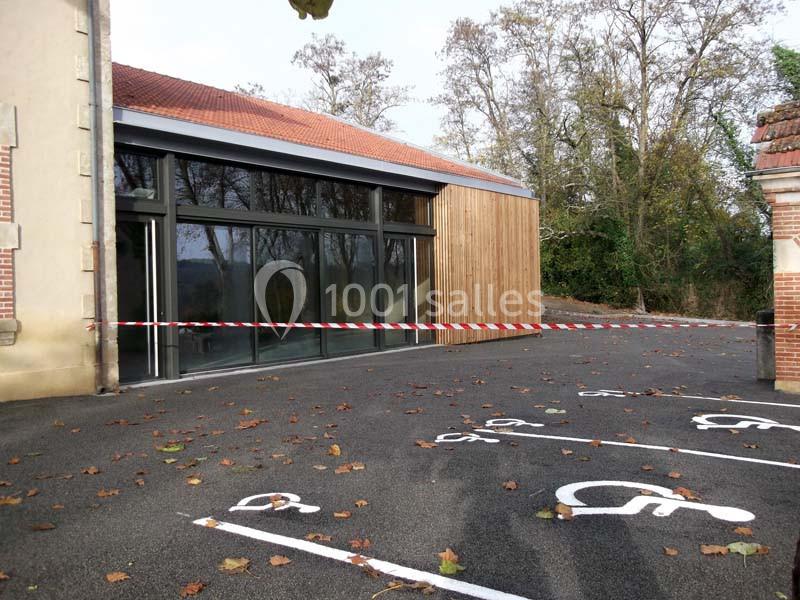 Façade d'un bâtiment moderne avec des places de stationnement réservées aux personnes handicapées au premier plan.