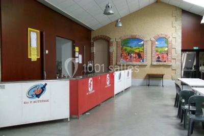 Des personnes assises et debout discutent dans une salle conviviale avec des tables, des chaises et des décorations murales.