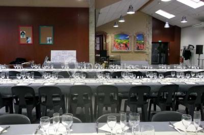Des personnes assises et debout discutent dans une salle conviviale avec des tables, des chaises et des décorations murales.