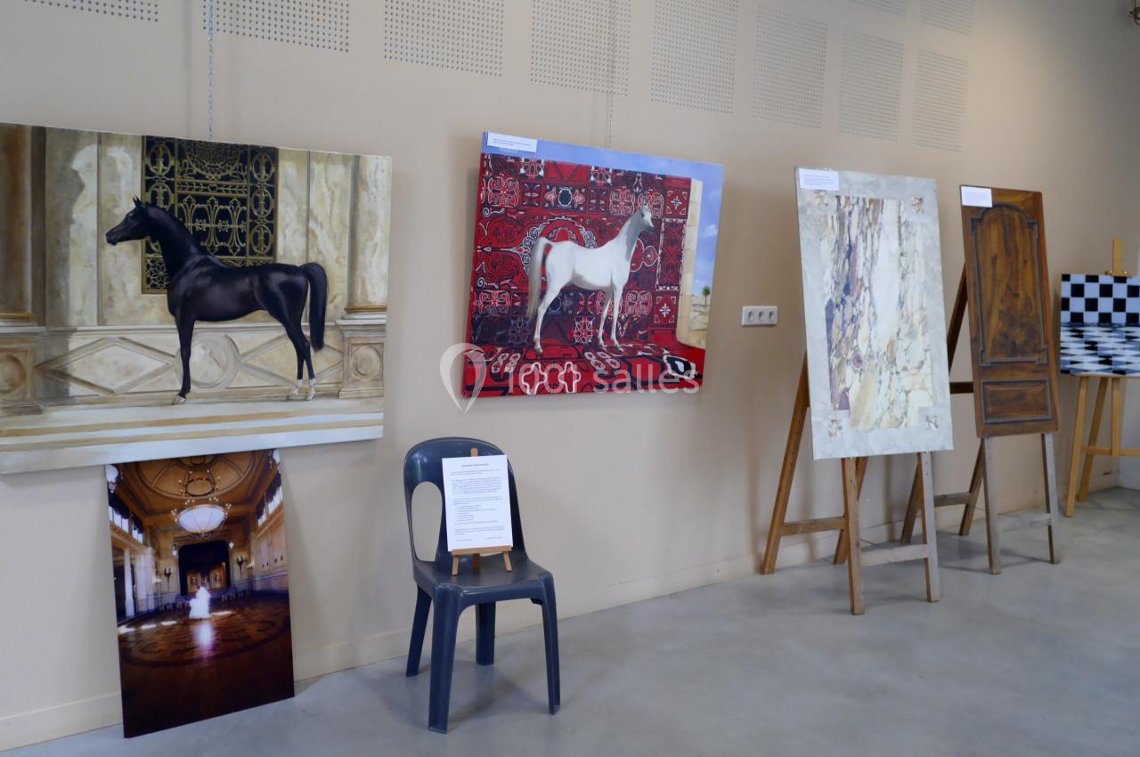 Exposition d'art avec des peintures de chevaux, une photographie d'intérieur et des œuvres abstraites sur chevalets.