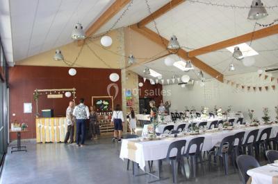 Des personnes assises et debout discutent dans une salle conviviale avec des tables, des chaises et des décorations murales.