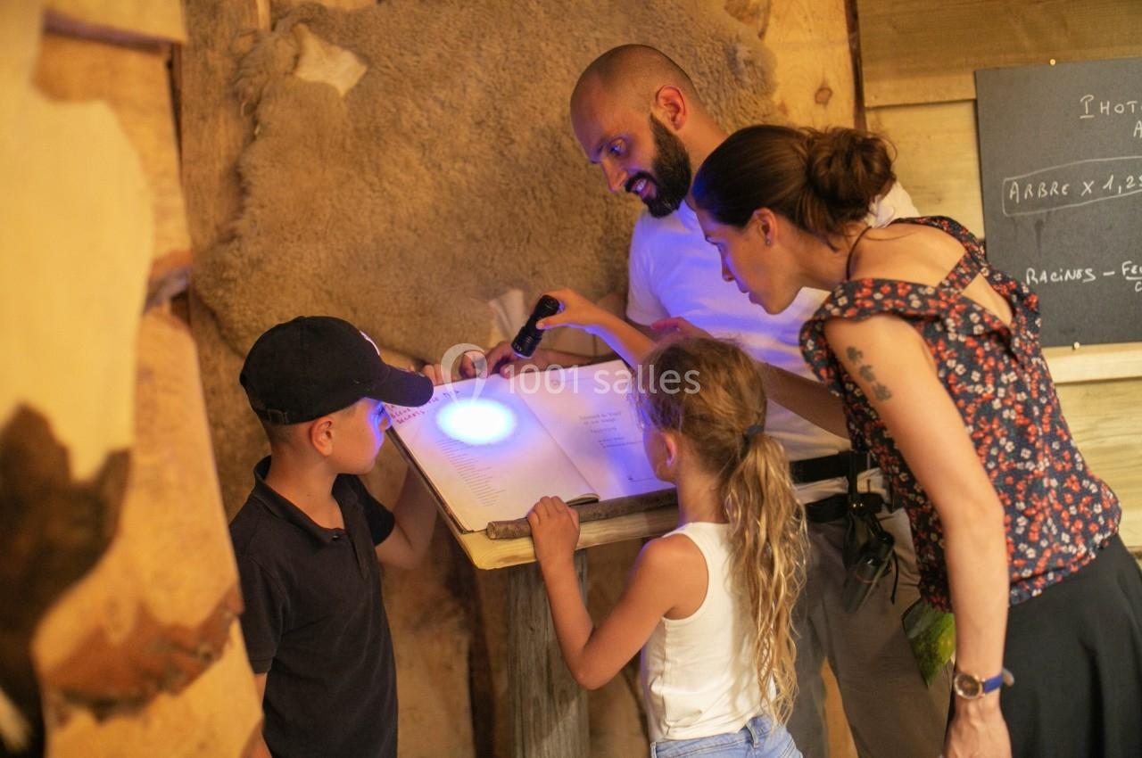 Un groupe de personnes examine un document éclairé par une lampe UV dans un environnement en bois.