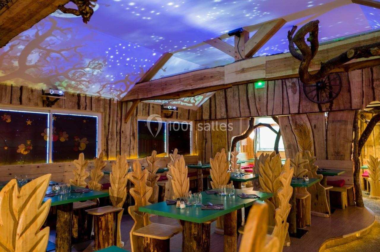 Salle de restaurant à thème forestier avec tables en bois, chaises sculptées en forme de feuilles et éclairage tamisé.