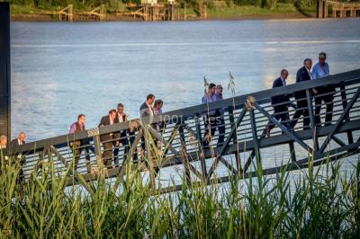 Vue d'une salle de bain avec double vasque en bois et d'une chambre lumineuse avec parquet et grandes fenêtres.