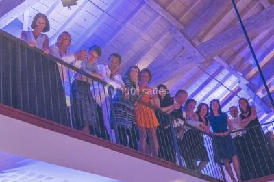 Vue d'une salle de bain avec double vasque en bois et d'une chambre lumineuse avec parquet et grandes fenêtres.