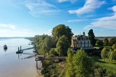 Salle de réception décorée avec des tables rondes, nappes blanches, chandeliers et arrangements floraux élégants.