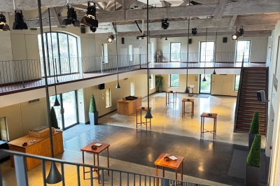 Salle de réception décorée avec des tables rondes, nappes blanches, chandeliers et arrangements floraux élégants.
