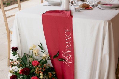 Salle de réception décorée avec des tables rondes, nappes blanches, chandeliers et arrangements floraux élégants.