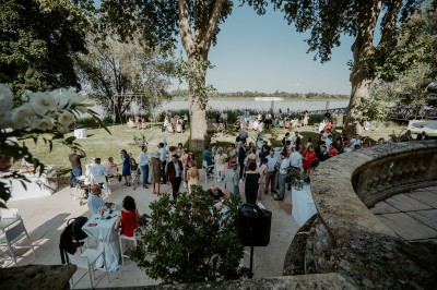 Salle de réception décorée avec des tables rondes, nappes blanches, chandeliers et arrangements floraux élégants.