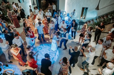 Salle de réception décorée avec des tables rondes, nappes blanches, chandeliers et arrangements floraux élégants.