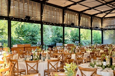 Salle de réception décorée avec des tables rondes, nappes blanches, chandeliers et arrangements floraux élégants.