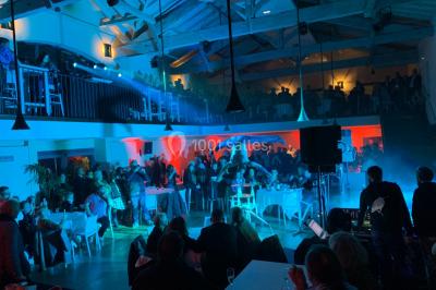 Vue d'une salle de bain avec double vasque en bois et d'une chambre lumineuse avec parquet et grandes fenêtres.