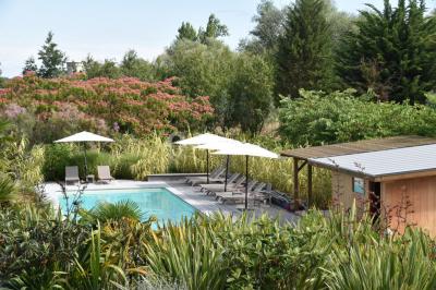 Vue d'une salle de bain avec double vasque en bois et d'une chambre lumineuse avec parquet et grandes fenêtres.