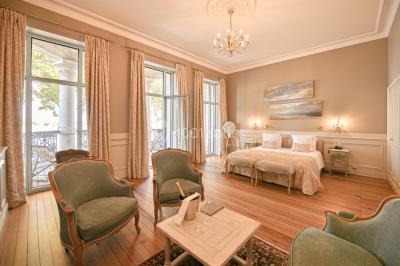Vue d'une salle de bain avec double vasque en bois et d'une chambre lumineuse avec parquet et grandes fenêtres.