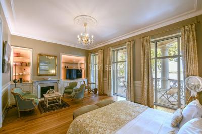 Vue d'une salle de bain avec double vasque en bois et d'une chambre lumineuse avec parquet et grandes fenêtres.