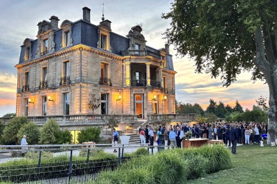 Salle de réception décorée avec des tables rondes, nappes blanches, chandeliers et arrangements floraux élégants.