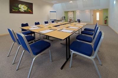 Buffet de petit-déjeuner avec viennoiseries, fruits, céréales et boissons, présenté dans une salle lumineuse.